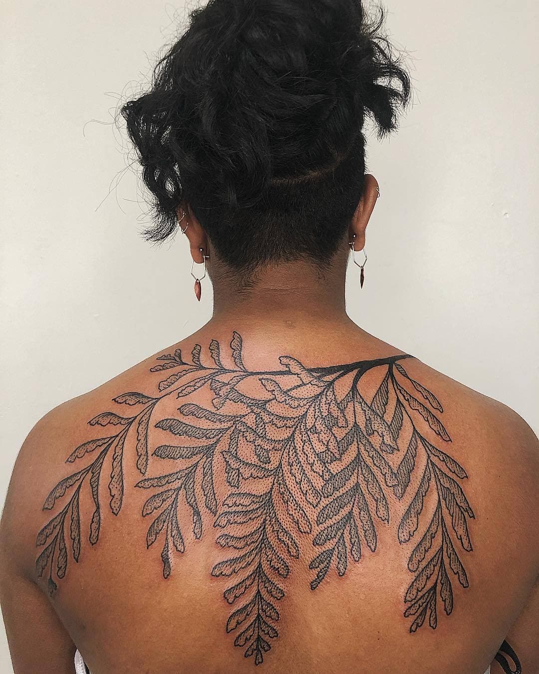 Brown person's tattooed back highlighted in a circle